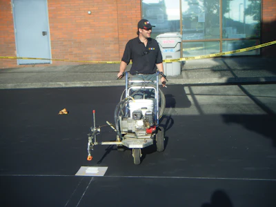 Nathan Witthuhn, owner of DMO Striping, is pictured completing striping work. DMO Striping offers services including crack fill, striping, sealcoating and infrared asphalt repair.