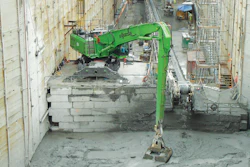 The operator of the SENNEBOGEN 870 M scoops up tailings with a custom clamshell bucket.