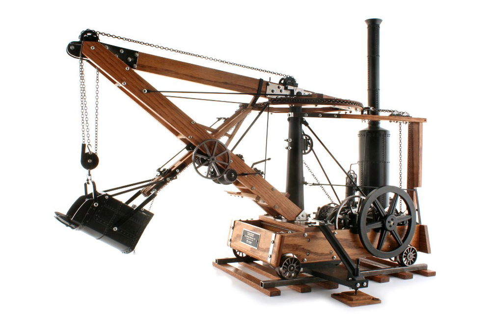 This 1:10 scale working model of the Otis Shovel patented in 1839 features a swinging boom, extending and retracting dipper stick, rolling wheels, and operational levers, gears, drums and bucket trip.