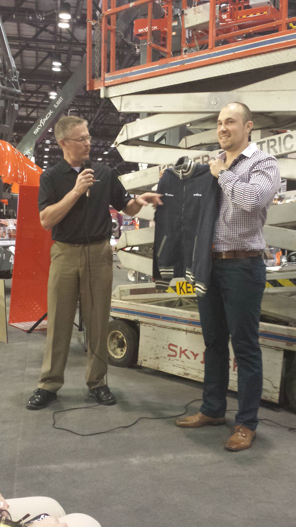 Matthew Kraner, co-owner of Kraner Electric Ltd. in Guelph, Ontario, Canada, is shown accepting a vintage jacket that commemorates the honor of owning the oldest working Skyjack scissor lift.