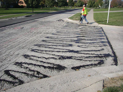 Improper application of tack coats, like this tack that was applied by hand using a pour bucket, eliminates any benefits that can result from using tack coats to improve paving.