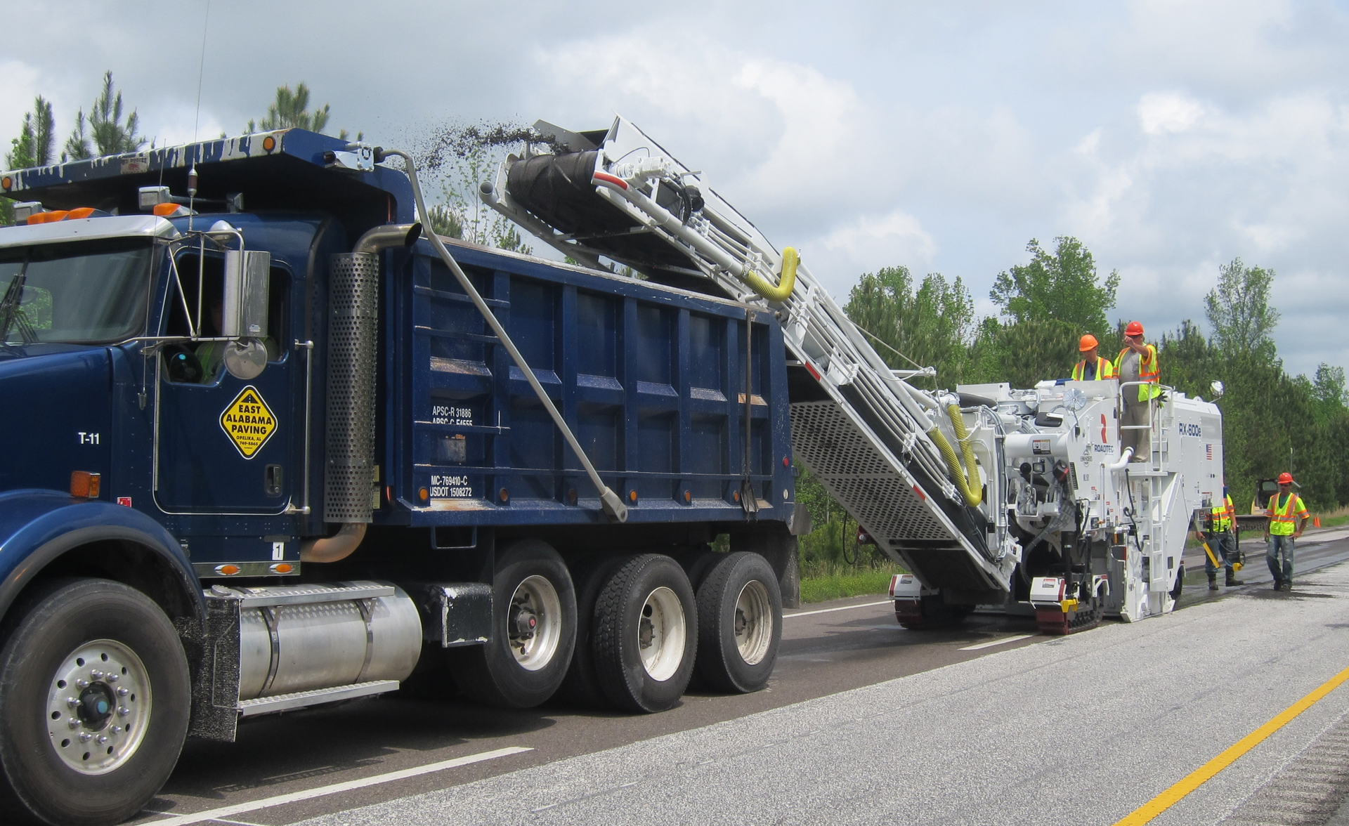 The Roadtec RX-600e, RX-700e, and RX-900e models include a dust extraction system which uses a hydraulic fan to remove dust from the primary conveyor and channel the material to the dump truck alongside the secondary conveyor.