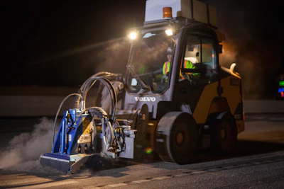 Nighttime motorists driving along the I-5 highway may spot the Volvo MC115C skid steer at work removing reflective pavement markers from the pavement.