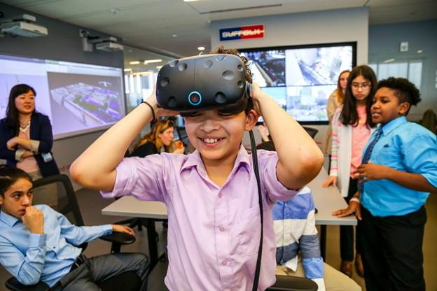 A seventh grader from DREAM tries on VR goggles in the Smart Lab during a visit to the Suffolk offices.