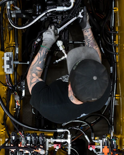 Zach Clark is an assembler with Weiler. He is installing hydraulic lines to the hydraulic pump of a Weiler road widener.