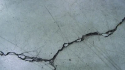 Unrestricted crack width growth leads to spalled edges along out-of-joint cracks when exposed to wheeled traffic.