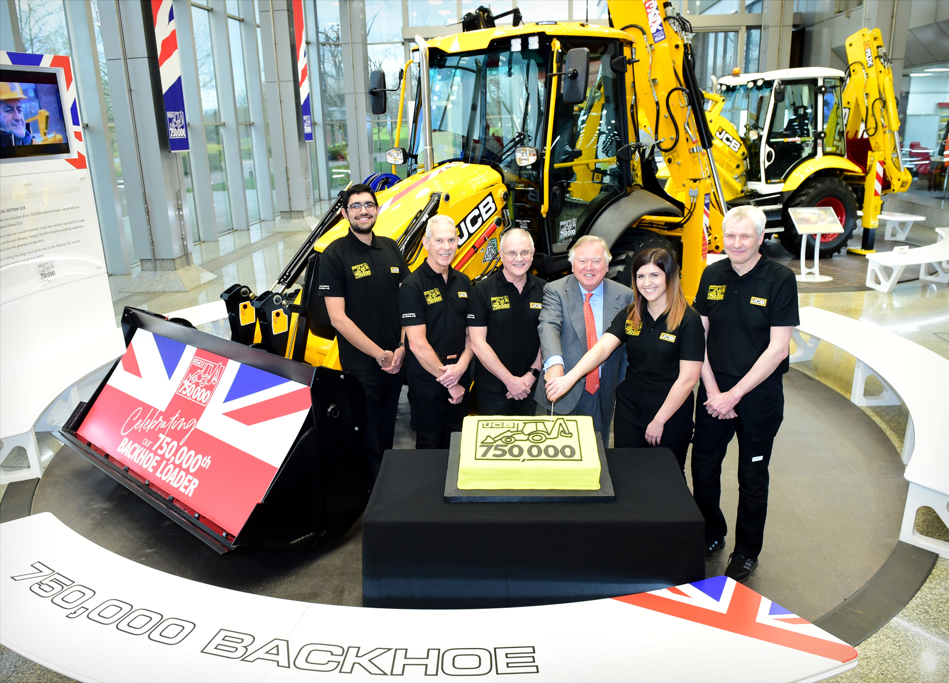 Pictured left to right: JCB backhoe loader employees Nihal Dhillon, Phil Starbuck, John Plant, JCB Chairman Lord Bamford, Shannon Ramczykowski and Keith Bloor celebrating the production of the 750,000th JCB backhoe loader at JCB World HQ, Rocester, Staffordshire.