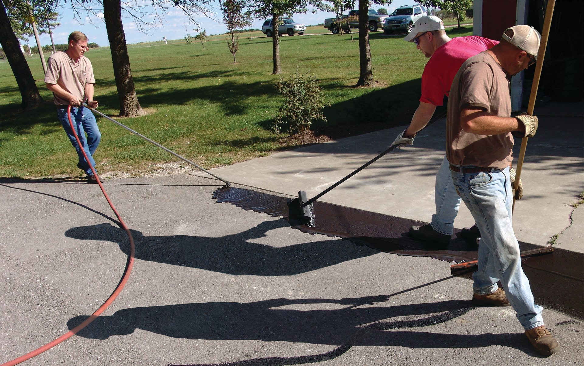 Use a brush and squeegee to spread the sealcoat out on the pavement