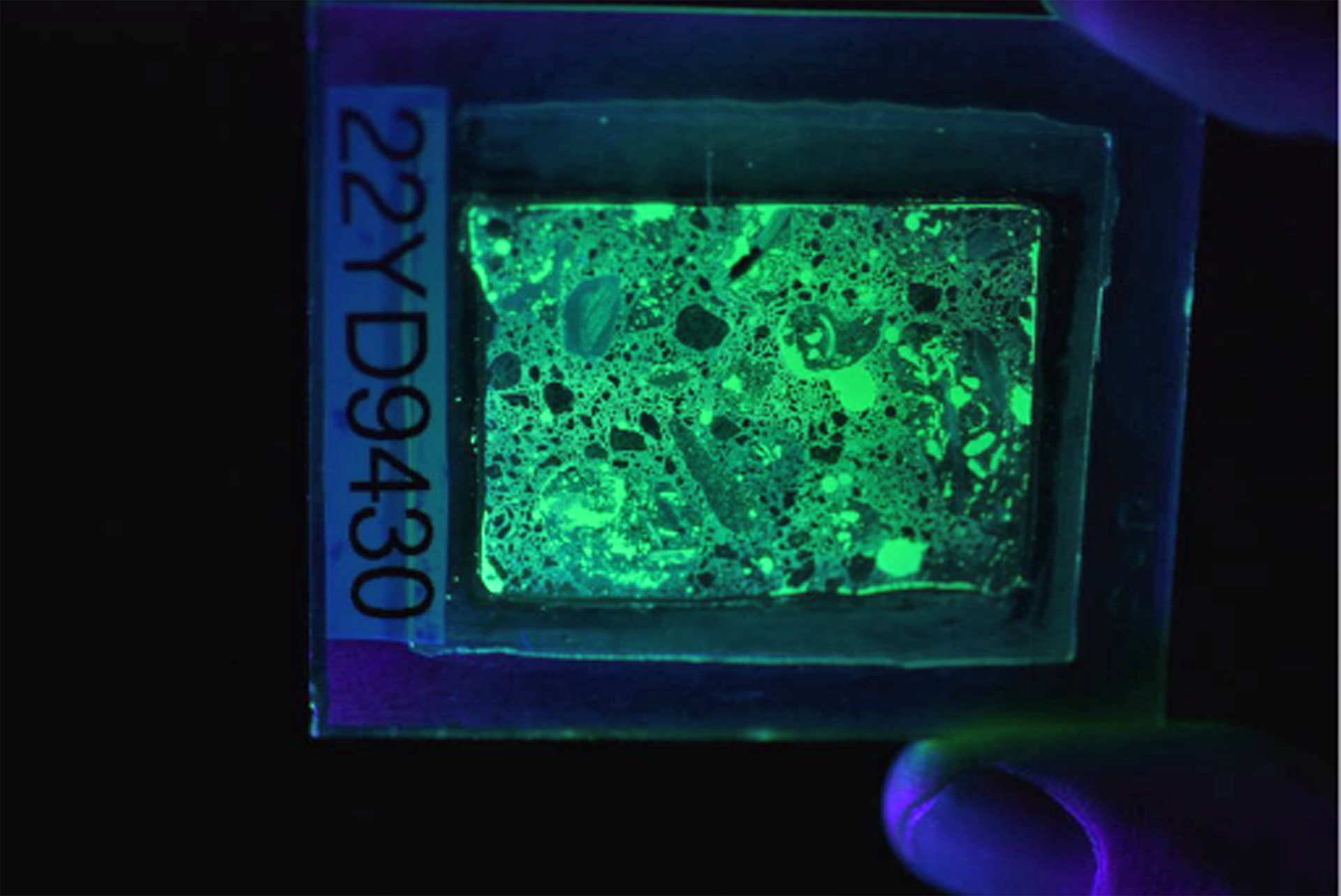 Figure 2. Photograph of a fluorescent thin section in UV light, which makes the concrete glow.