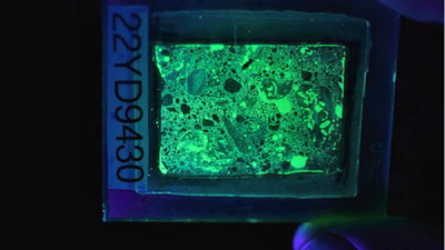 Figure 2. Photograph of a fluorescent thin section in UV light, which makes the concrete glow.