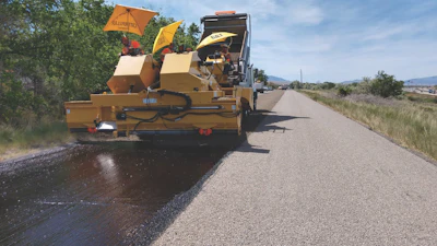 Crews place aggregate over oil emulsion