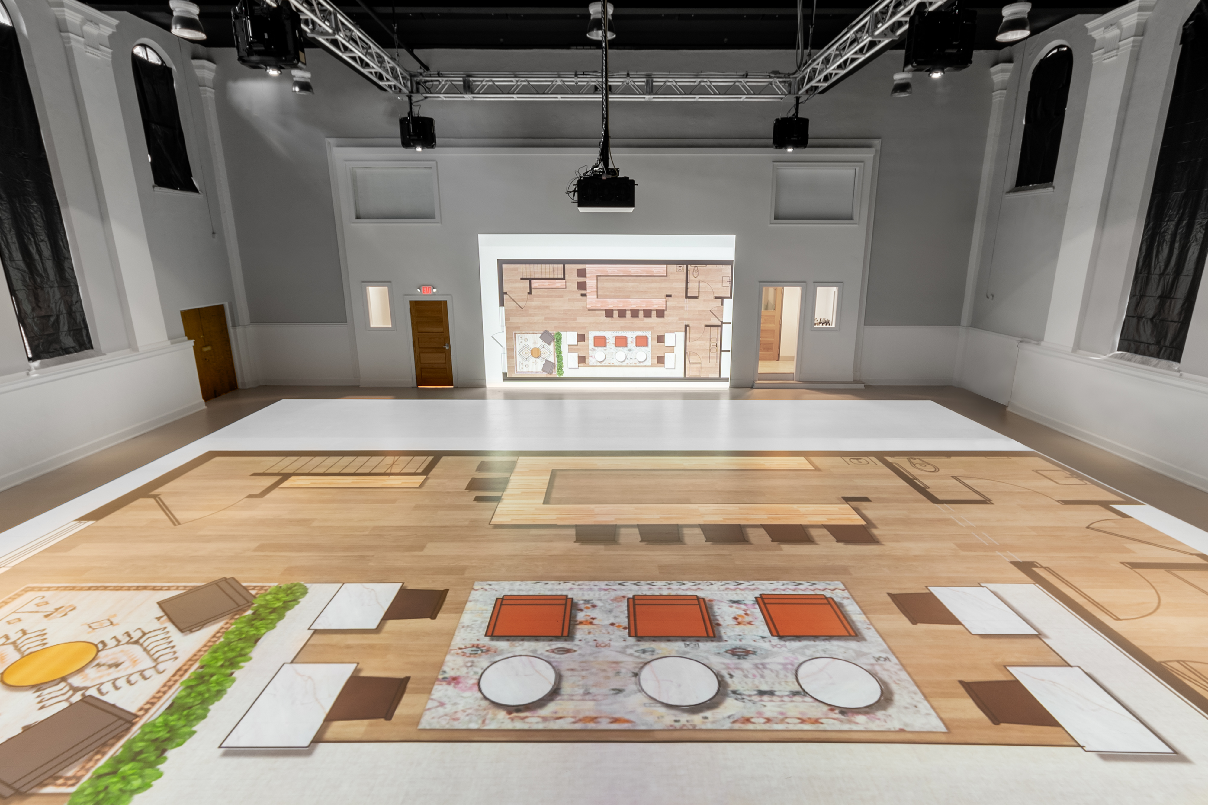 The company utilizes a multifaceted projection approach, displaying building plans on the floor as well as the adjacent wall, providing elevation readings such as countertops, windows and built-in bookshelf heights.