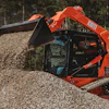 Powered by a 74-hp diesel engine, the machine offers two-speed travel, pilot hydraulic joystick controls, rearview camera, sliding overhead door and LED work lights.