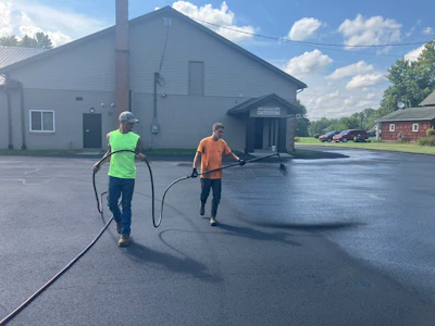 Pave Care employees Claude Whiteside and Christian Shaffer seal coating at Beloved Disciple Catholic Church.