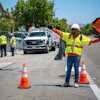 Road construction worker managing traffic with SLOW sign on suburban street