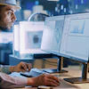 Technical worker analyzing data on dual monitors in industrial control center