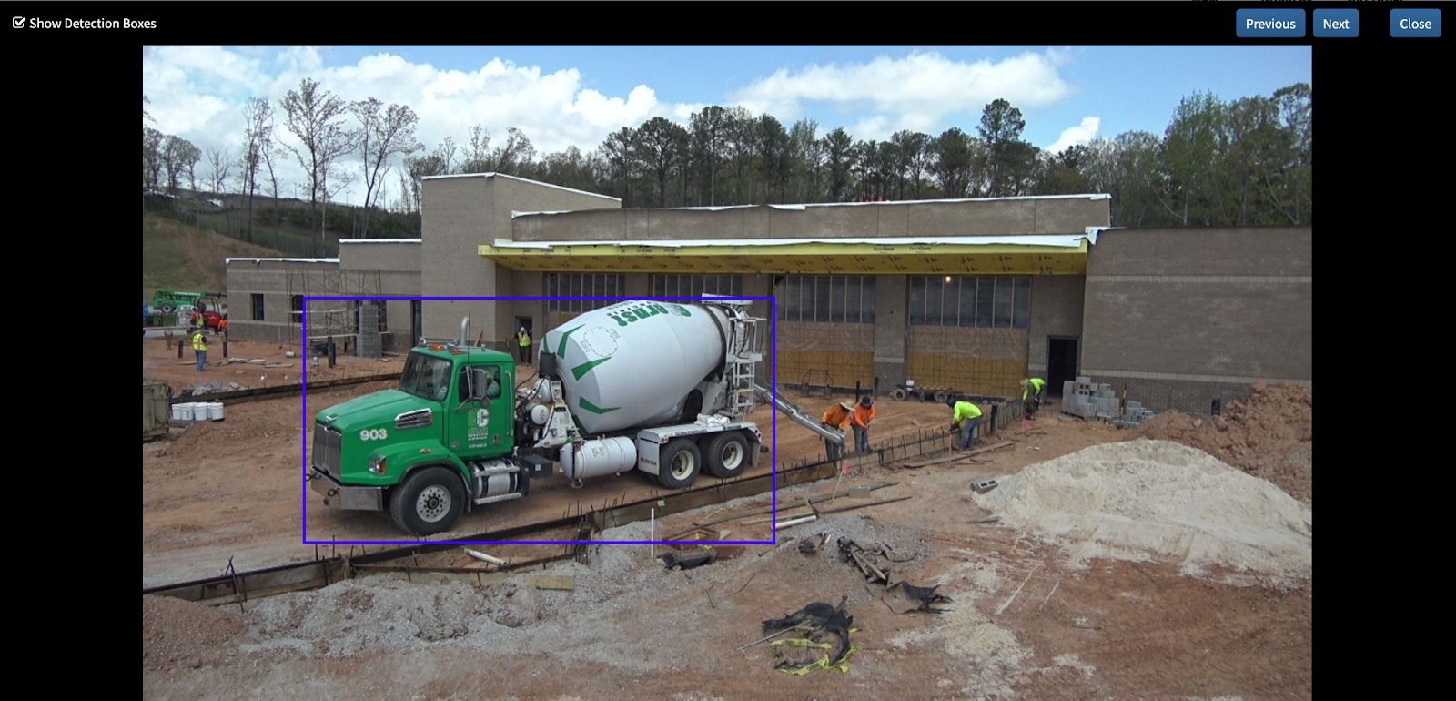 Green cement mixer truck at construction site with workers preparing building foundation