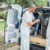Painter organizing tools in white van parked on residential street
