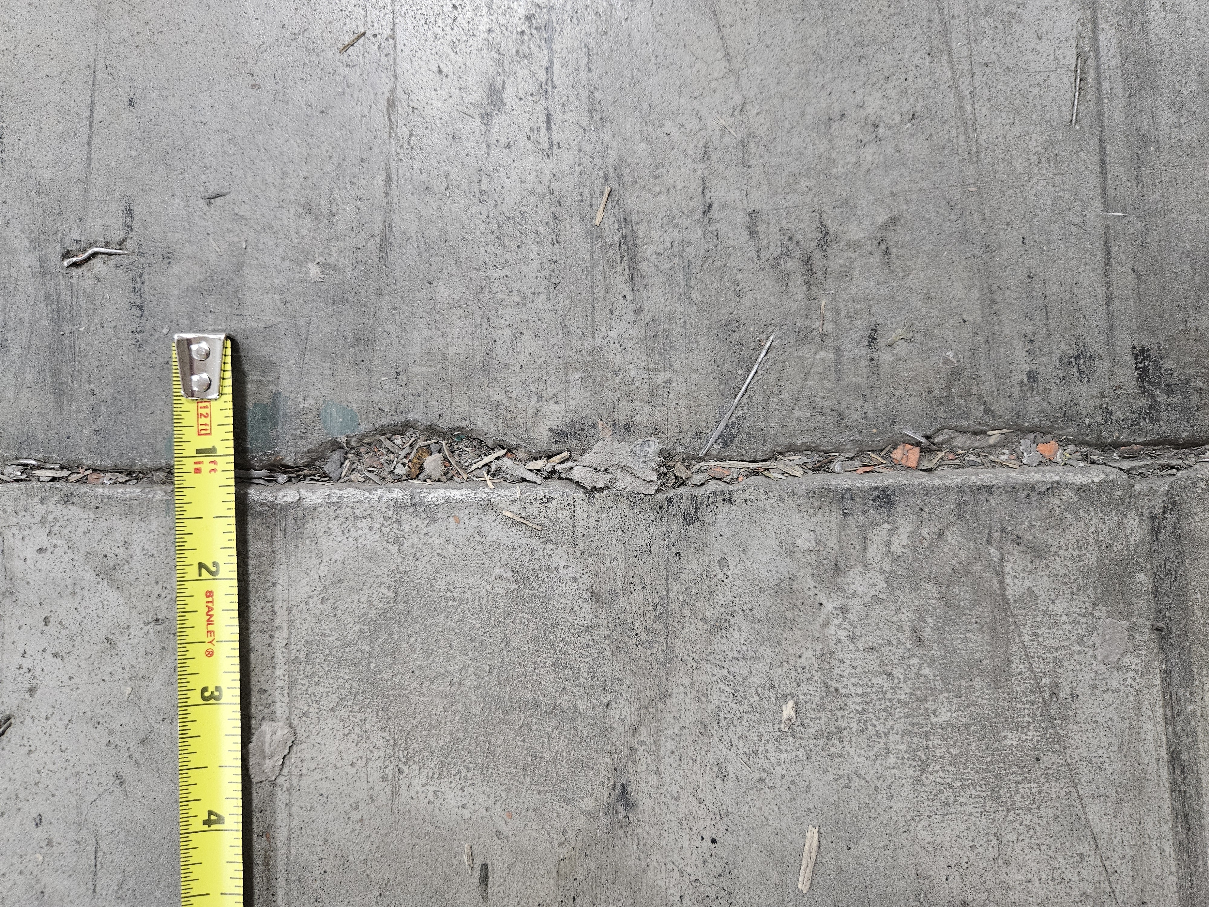 Concrete surface with yellow measuring tape showing surface texture and measurement details