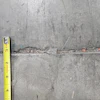 Concrete surface with yellow measuring tape showing surface texture and measurement details