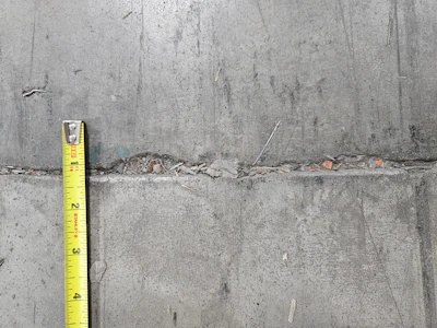 Concrete surface with yellow measuring tape showing surface texture and measurement details