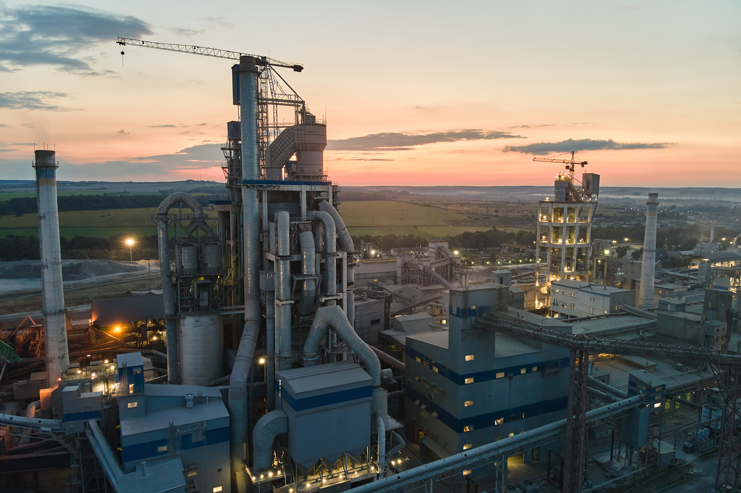 Industrial manufacturing facility at sunset with complex machinery and illuminated infrastructure
