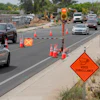 Road construction zone with safety cones, traffic signal, and vehicles navigating restricted lane