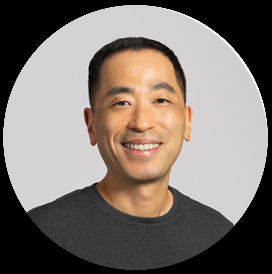 Smiling professional in gray shirt against neutral background Headshot