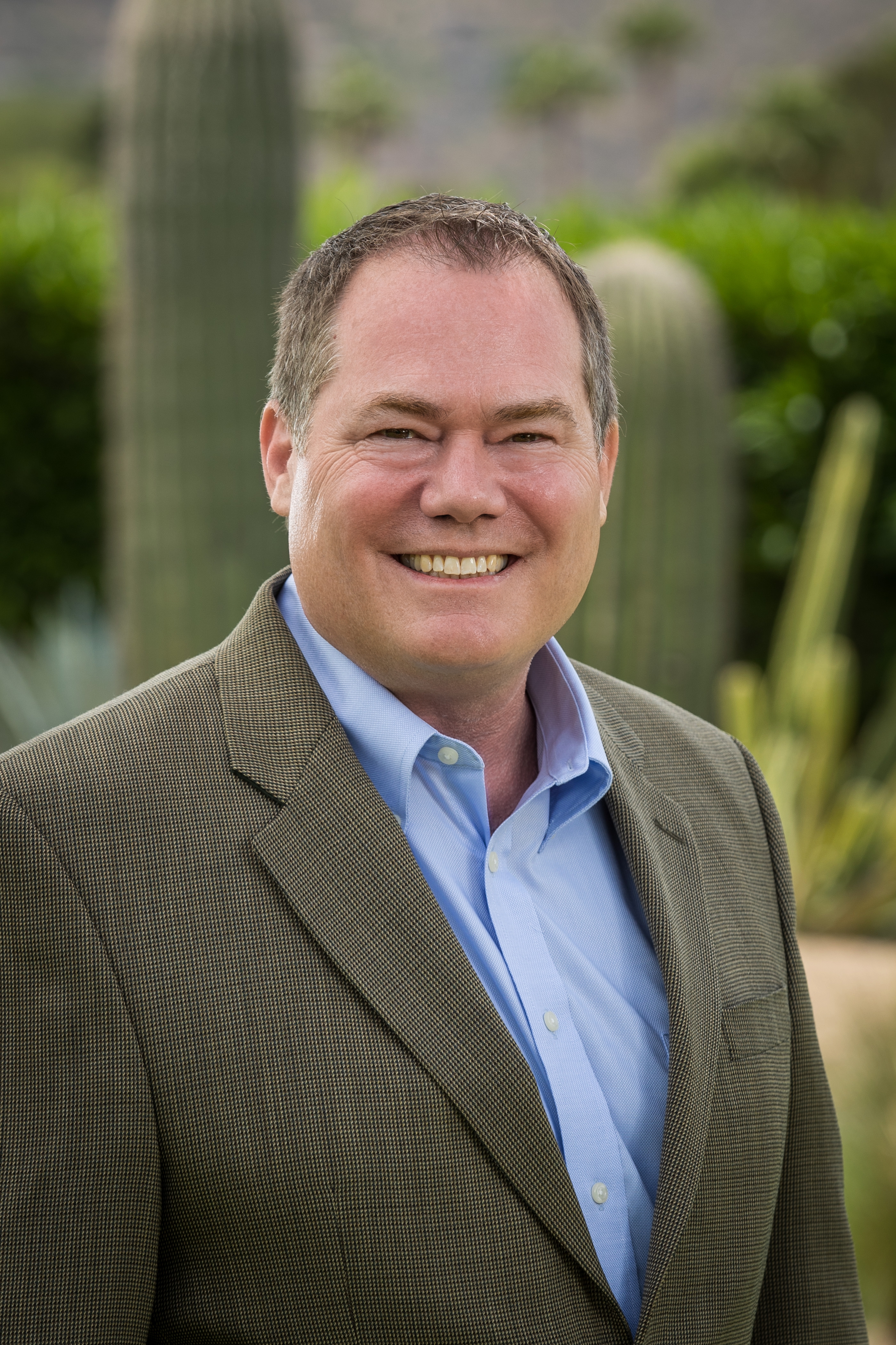 Smiling professional in business attire against desert botanical landscape Headshot