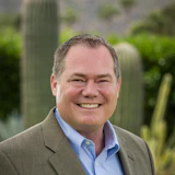 Smiling professional in business attire against desert botanical landscape