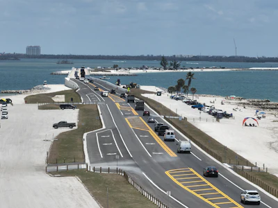 Coastal highway spanning sandy beach with multi-lane road and ocean views