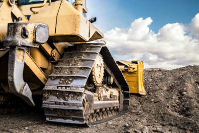 Yellow bulldozer on rocky ground with heavy-duty tracks and cloudy sky