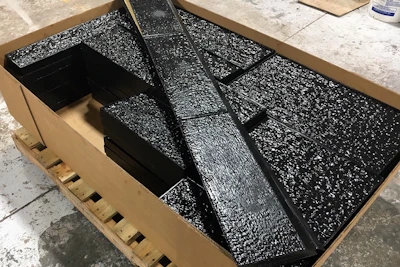 Fractured black glass tiles with textured surface packed in shipping container