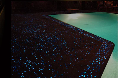 Swimming pool with luminous blue-dotted surface and teal water at night