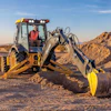 Yellow backhoe digging in desert terrain with yellow safety cones