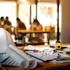Engineering workspace with white hard hat, blueprints, and tools on wooden desk