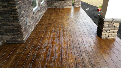 Wooden-textured stamped concrete patio with stone wall borders