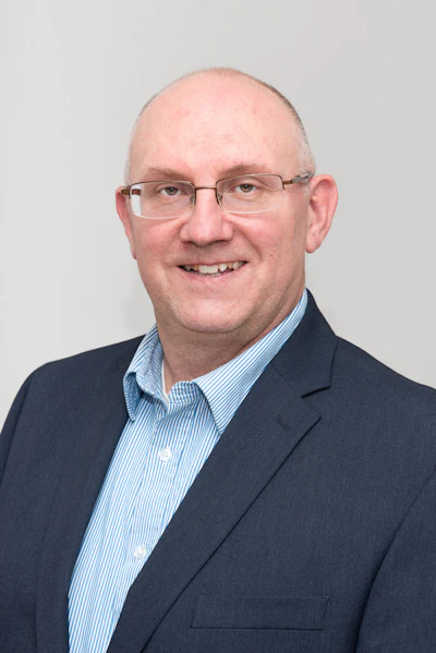 Smiling professional in navy blazer and blue striped shirt, wearing glasses