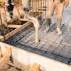 Construction workers preparing concrete foundation with steel reinforcement grid