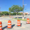 Construction site with orange traffic barrels and caution tape in parking lot