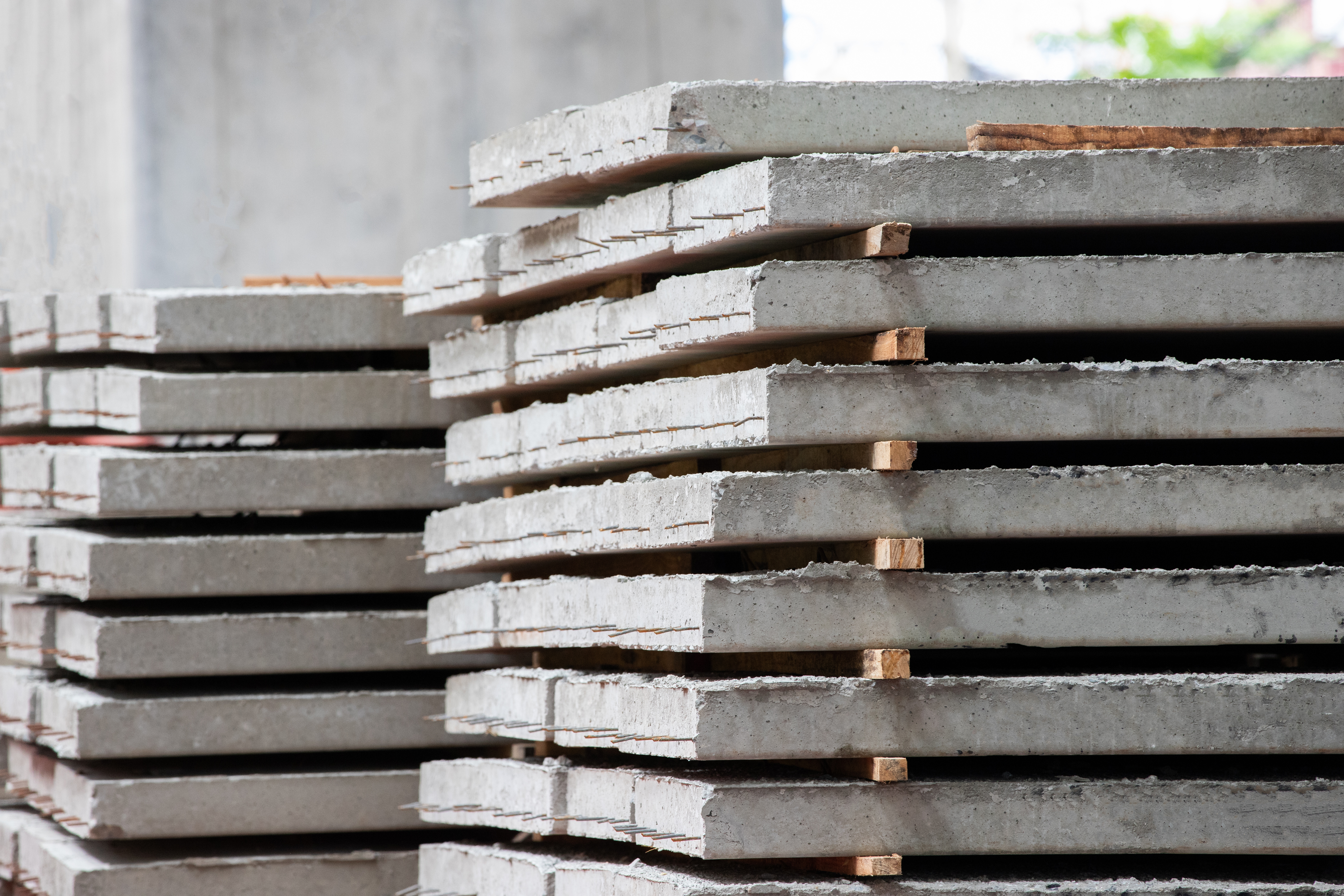 Stacked concrete construction panels with wooden spacers in industrial setting