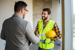 Construction worker in safety vest talking with colleague in office setting