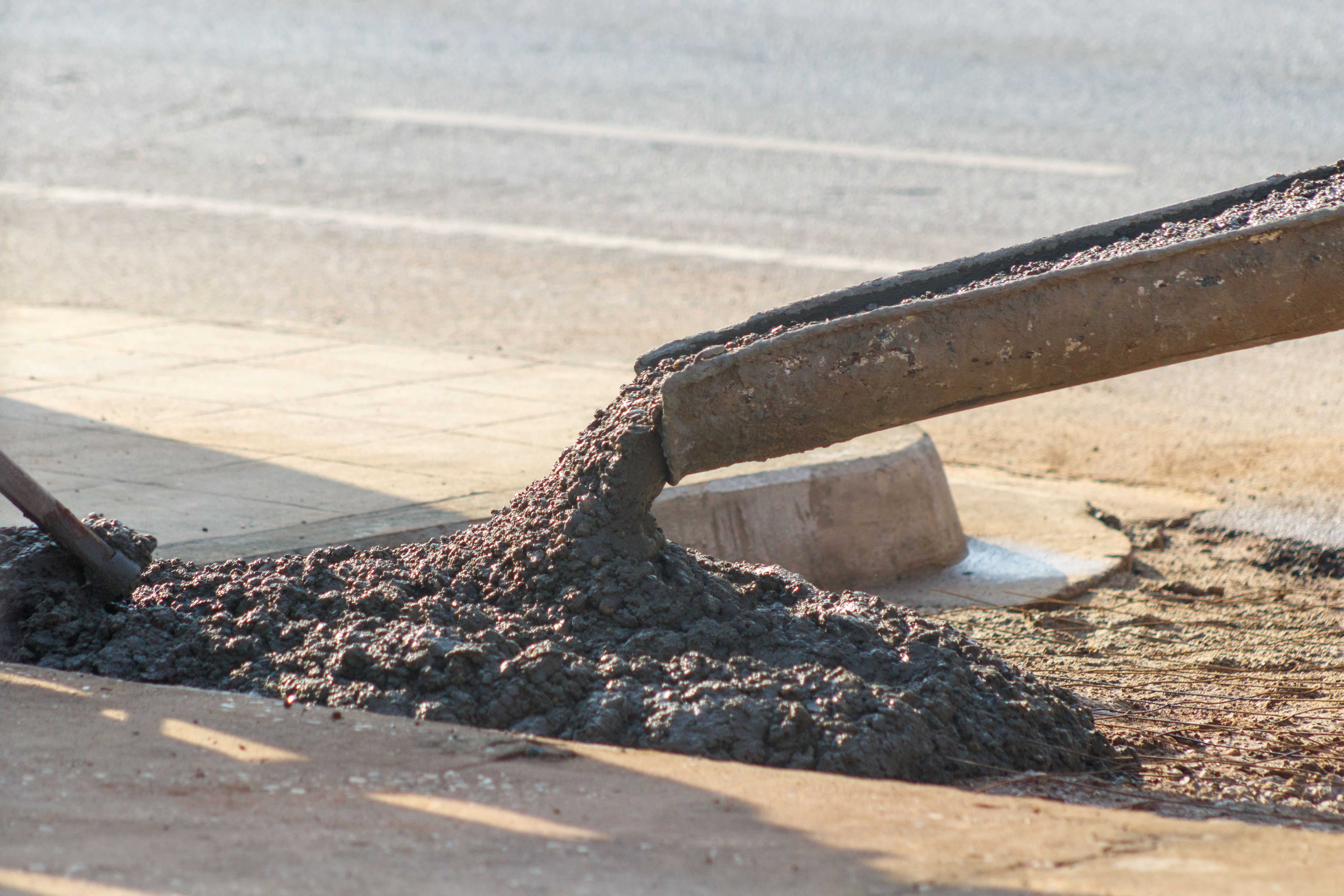 Wet concrete flowing from a construction chute onto a construction site surface