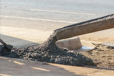 Wet concrete flowing from a construction chute onto a construction site surface