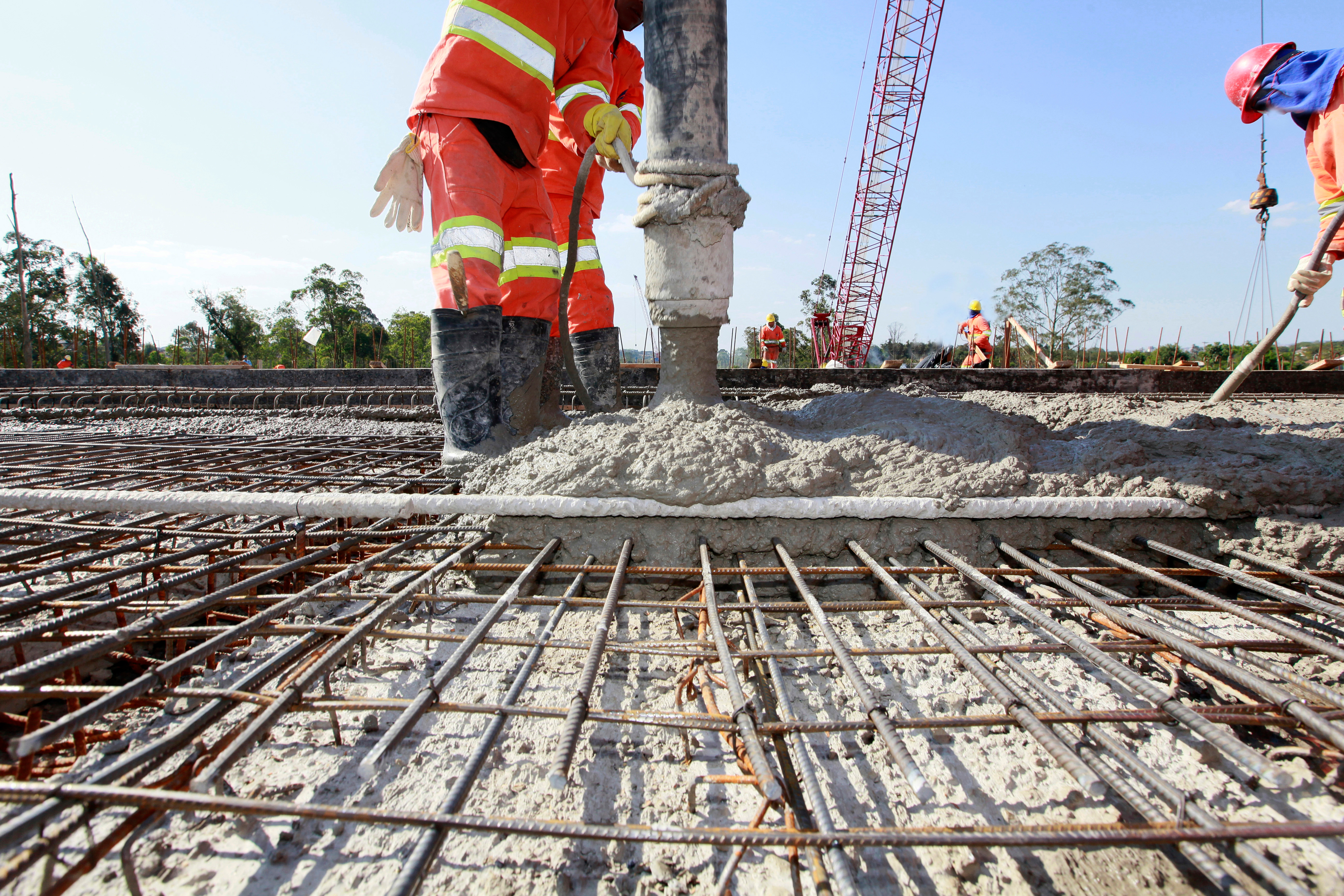 Construction workers pouring concrete over steel rebar grid at infrastructure project site