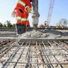Construction workers pouring concrete over steel rebar grid at infrastructure project site