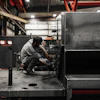Technician working on machinery in dimly lit industrial workshop