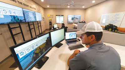 Industrial control room with worker monitoring screens and equipment displays