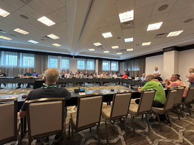 Large conference room with professionals gathered for a meeting around a U-shaped table