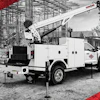 White utility service truck with crane at construction site with scaffolding